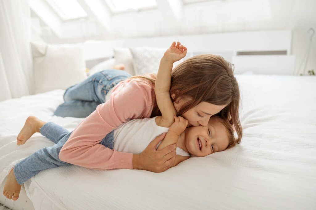Parent having fun with her little kid on bed