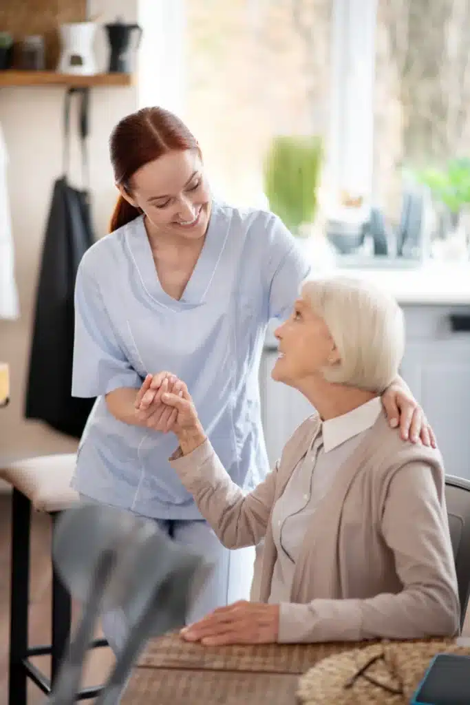 smiling young caregiver supporting pensioner after surgery