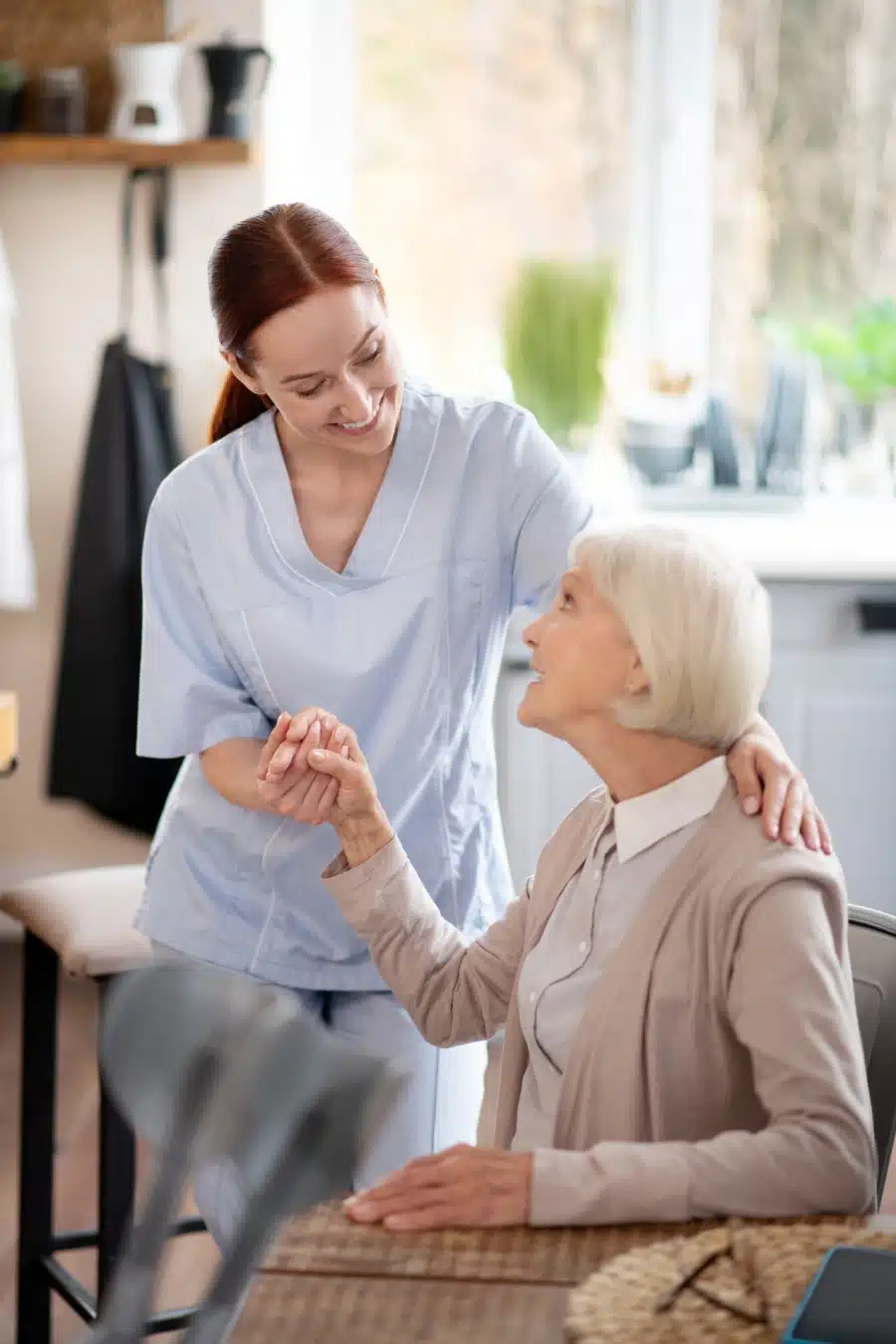 smiling young caregiver supporting pensioner after surgery