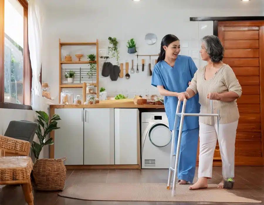 young caregiver helping senior woman walk beautifull kitchen