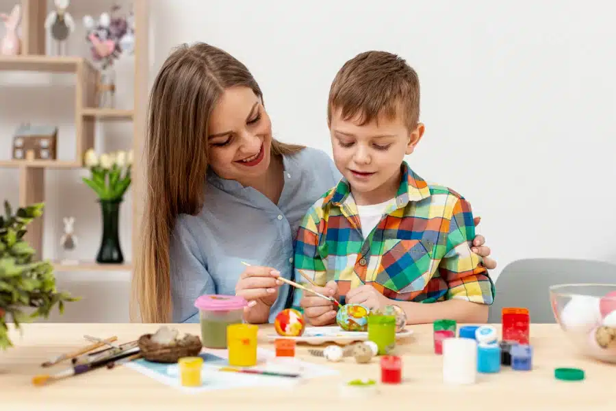 young mom son painting eggs easter